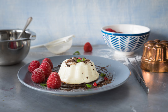 Beautifully plated vanilla panna cotta with chocolate sauce and fresh raspberries