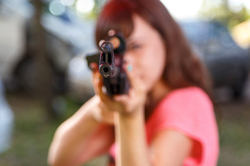 Young woman shooting from telescopic air gun, focus on front sig