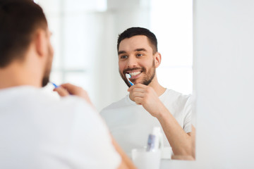 man with toothbrush cleaning teeth at bathroom - Powered by Adobe