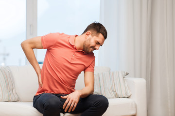 unhappy man suffering from backache at home - obrazy, fototapety, plakaty