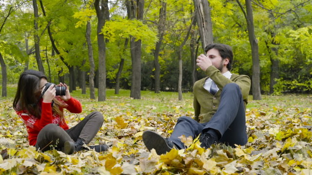 young female taking photos of a man in the autumn park slow motion