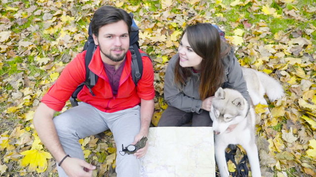 top view of happy hikers watching to the camera and a dog in the autumn forest  