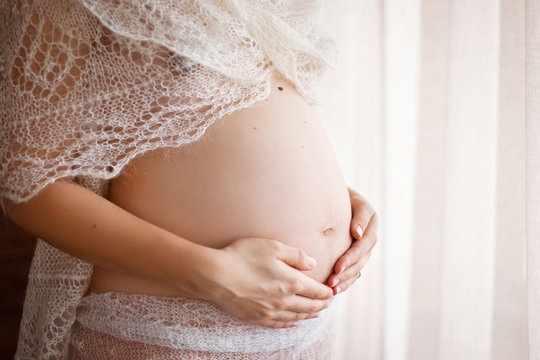 Close-up image of pregnant woman touching her belly with hands