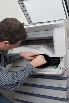 Male technician repairing digital photocopier machine