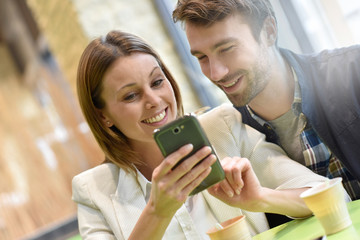 Couple sitting at coffee shop and using smartphone