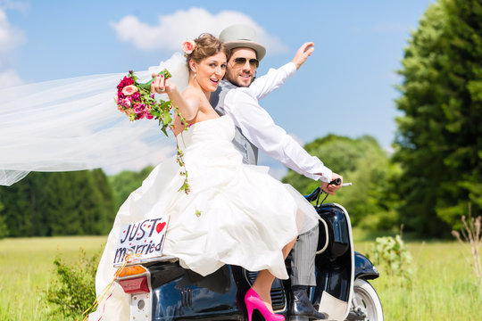 Hochzeit Bräutigam und Braut fahren mit Motorroller und haben Spaß