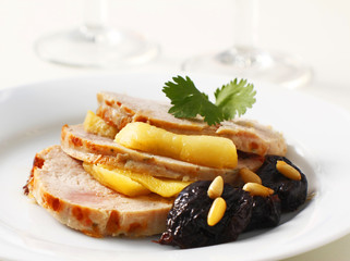 Slices of a turkey roll rerved with apple, plumbs and pine seeds