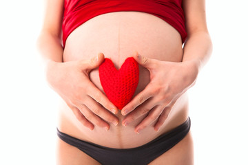 pregnant woman's belly with red knitted heart, concept of  love,