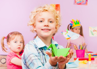 Handsome blond boy shows origami in classroom