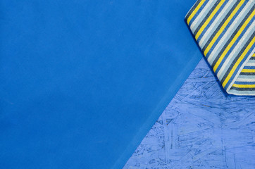 A blue themed background with pressed wood, table cloth and folded dish towel