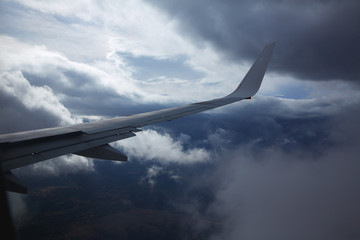 Fototapeta na wymiar Aircraft wing in a cloudy stormy clouds sky