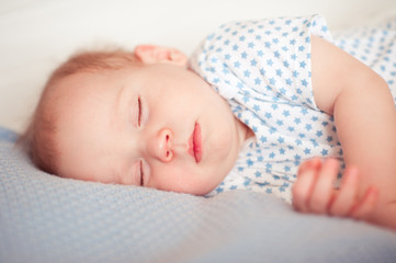 Cute baby sleeping in bed closeup. Lying in bed in room. Eyes closed. Childhood. 