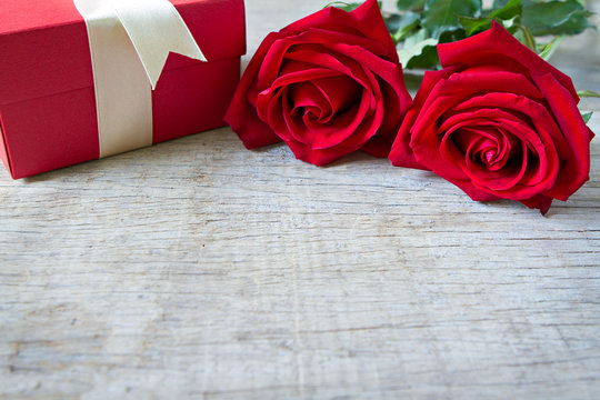 Red roses with red gift box on woonden background. Valentine's D