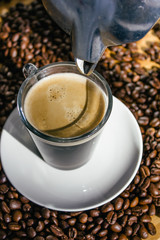 Coffee percolator and glass cup of coffee on coffee beans