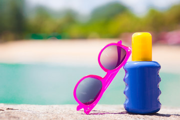 Sunscreen and sunglasses on sand at tropical beach