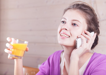 young woman talking on the phone and drinking orange juice. breakfast concept