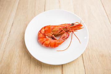 Shrimps on white dish over wood table