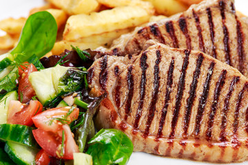 Grilled pork meat  with fried potatoes and vegetables
