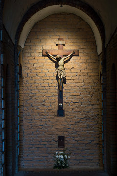 Dark artistic old cross on a shaded rough textured brick wall