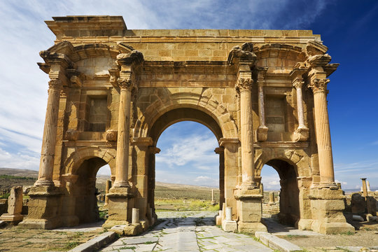 Algeria. Timgad (ancient Thamugadi). Paving stones of Decumanus Maximus street and 12 m high triumphal arch, called Trajan's Arch