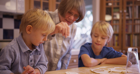 Two adorable white children making cookies with grandma