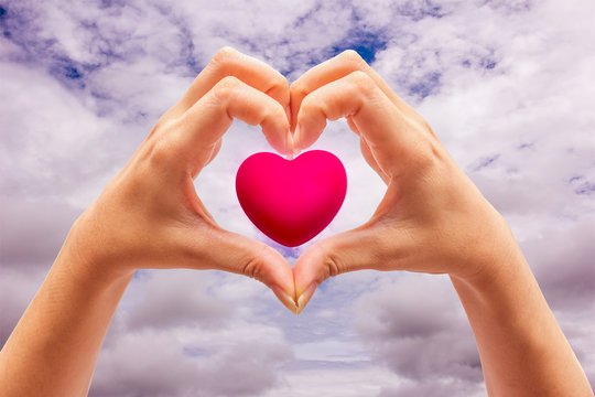 Pink Heart in hands on nature background