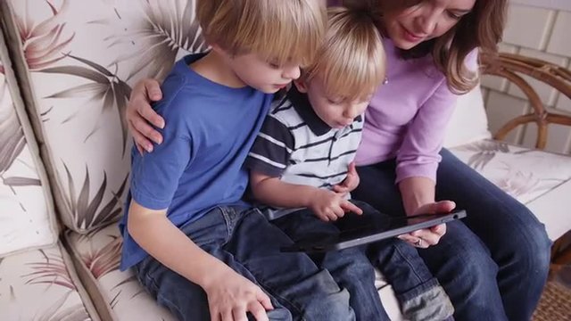 Mother and two sons reading a tablet computer