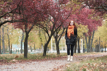 Fototapeta premium redhead girl walk on pathway in city park, fall season