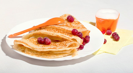 Pancakes on a white plate, with berries of a cranberry and cream