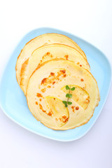 pancakes with apples and walnuts on a blue plate on a white background