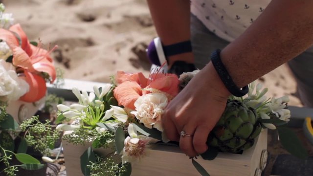 Woman hands decorate wooden flowerbed with different flowers for celebration.