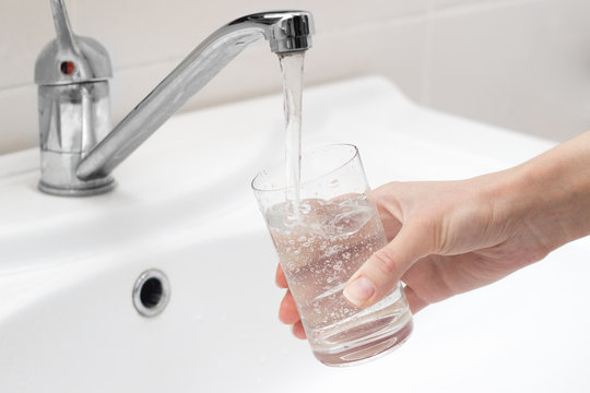person gaining cold drinking water from the tap