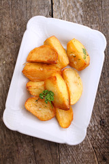 baked potatoes with spices in white bowl on an old wooden background