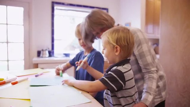 Elderly babysitter drawing with two cute white children