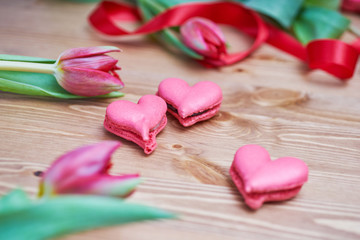 Naklejka na ściany i meble Heart-shaped macarons with flowers and ribbon on a wooden table. Creative decoration for Valentine's Day