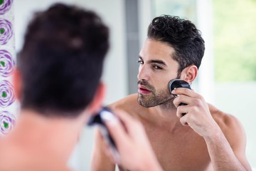 Handsome man shaving in the mirror