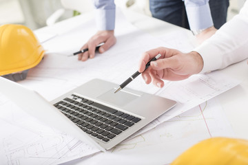 Business people on meeting in bright modern office with blueprint at desk check documents and business workflow on laptop