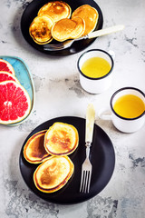 Fritters in black plates and two mugs of tea.
