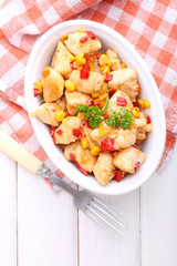 chicken with corn and bell pepper in a dish on a white background