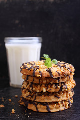 cookies with chocolate and nuts with a glass of milk on a dark background