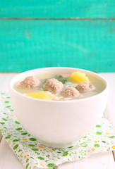 soup with potatoes, rice and meatballs in a white cup on a bright background
