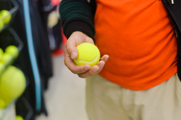 Hand choosing tennis ball for a tennis court on shop background