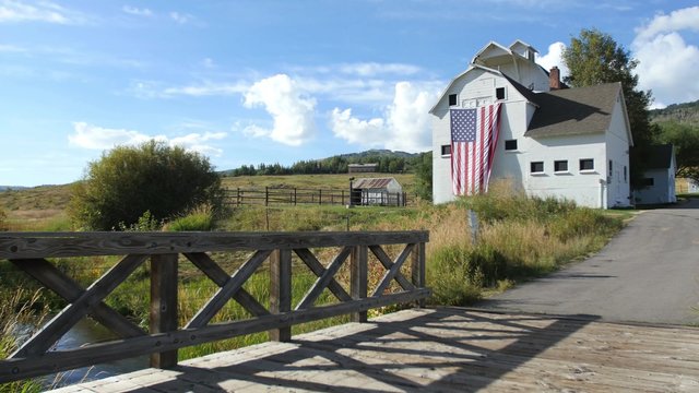 An American flag waves on the side of a picturesque white barn in the mountains outside of Park City, Utah.