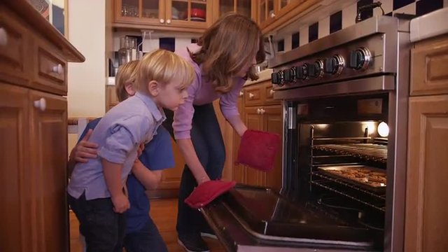 Charming mother baking cookies for her two boys