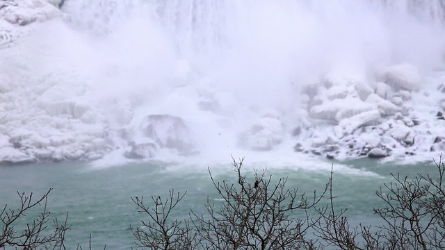 Winter snow Niagara falls shot six, trees in the foreground and the bottom of the falls in the background 