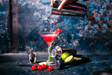 barman preparing and pouring red cocktail in marini class. cosmopolitan cocktail on metal background - obrazy, fototapety, plakaty