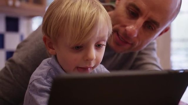 Portrait of a happy young boy reading an e-book with his father