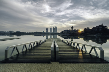 Obraz premium beautiful morning near the lakeside, modern building and wooden jetty. dramatic clouds and sunlight