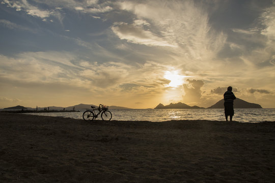Man with bicycle watching sunset at the beach