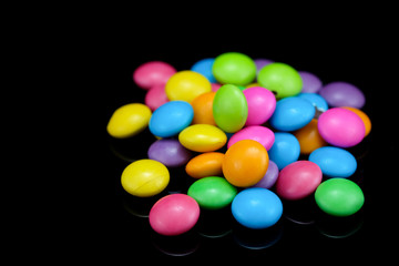 Chocolate candy in many colors on a black background.
